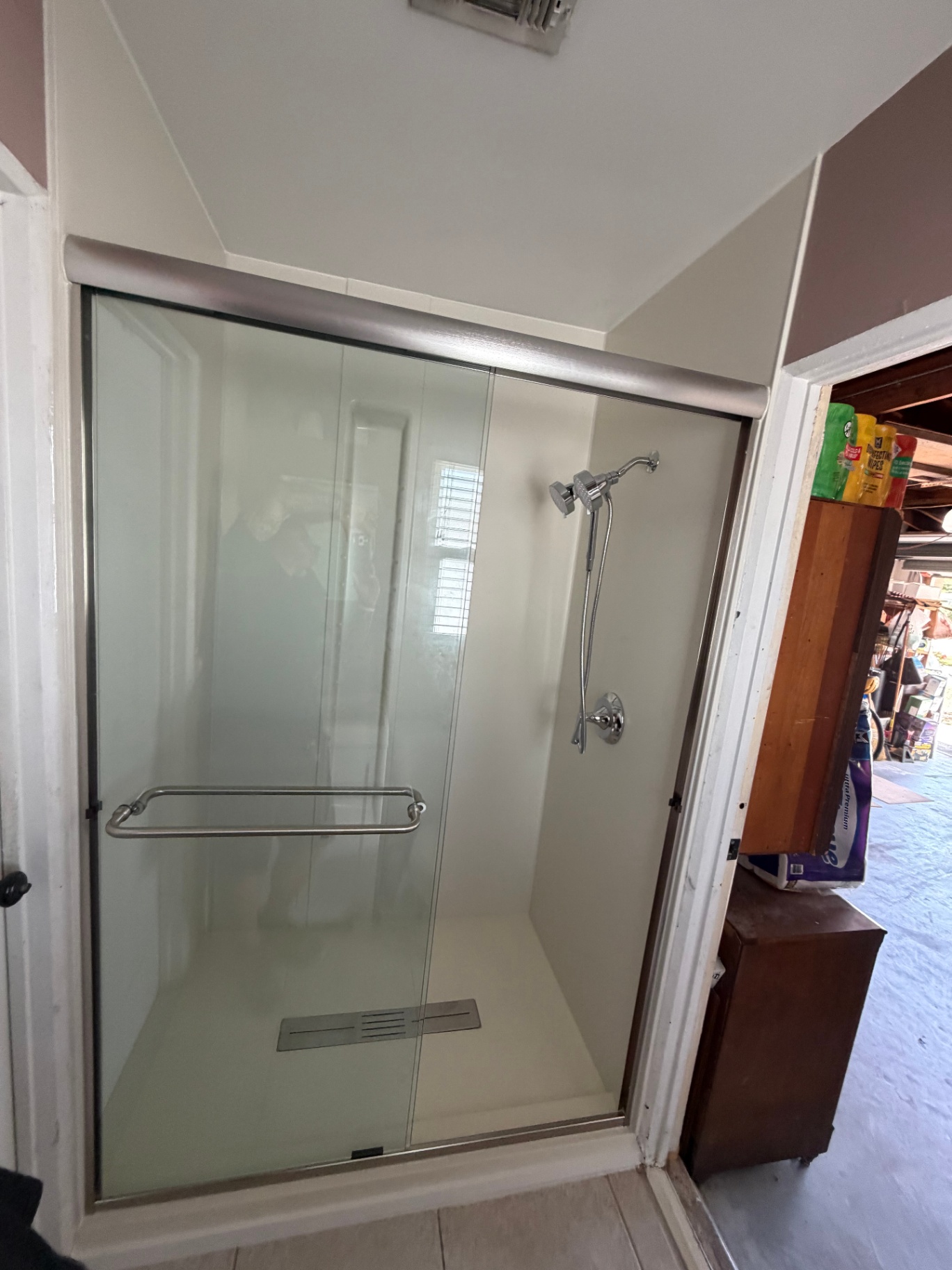 Sliding glass shower with smooth white acrylic walls and linear drain