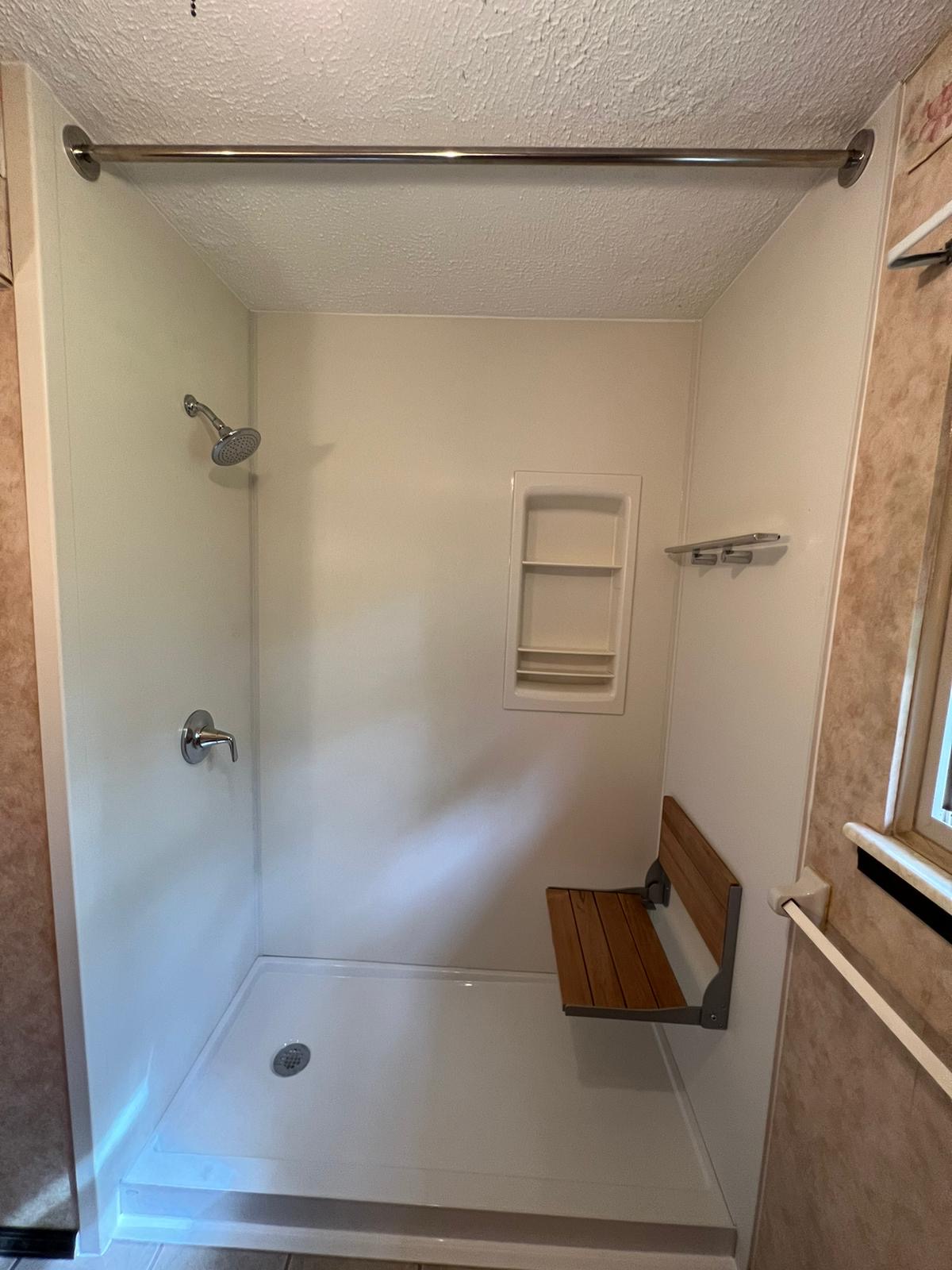 Walk-in shower with teak folding bench, recessed niche, and grab bar