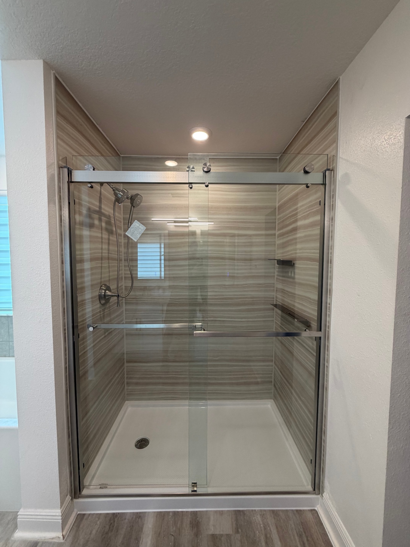 Frameless sliding glass shower with linen-textured wall panels