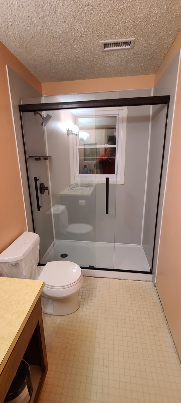 Walk-in shower with bronze-framed sliding glass and interior window