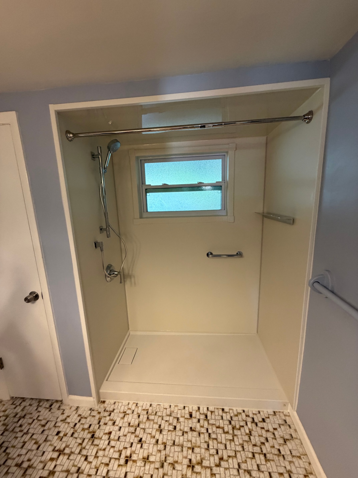 White acrylic shower stall with corner shelf and grab bar