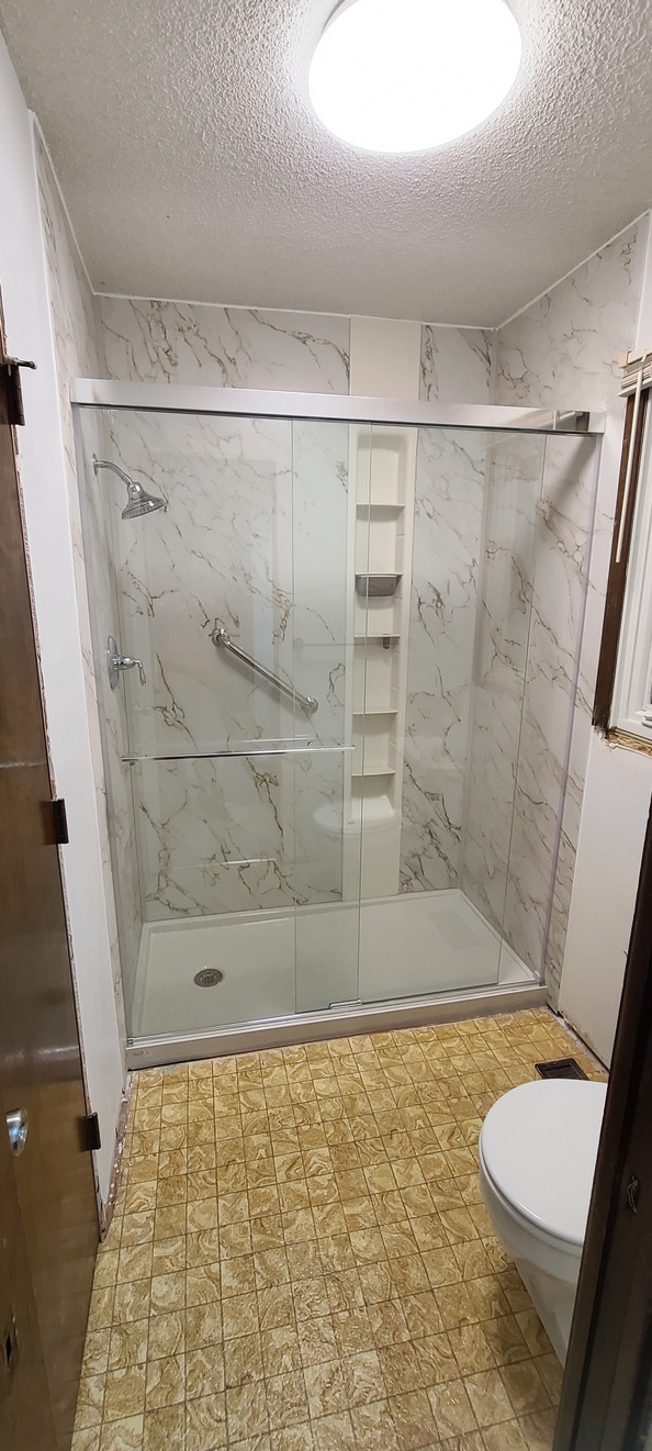 Walk-in shower with Calacatta marble-look acrylic walls and framed glass doors