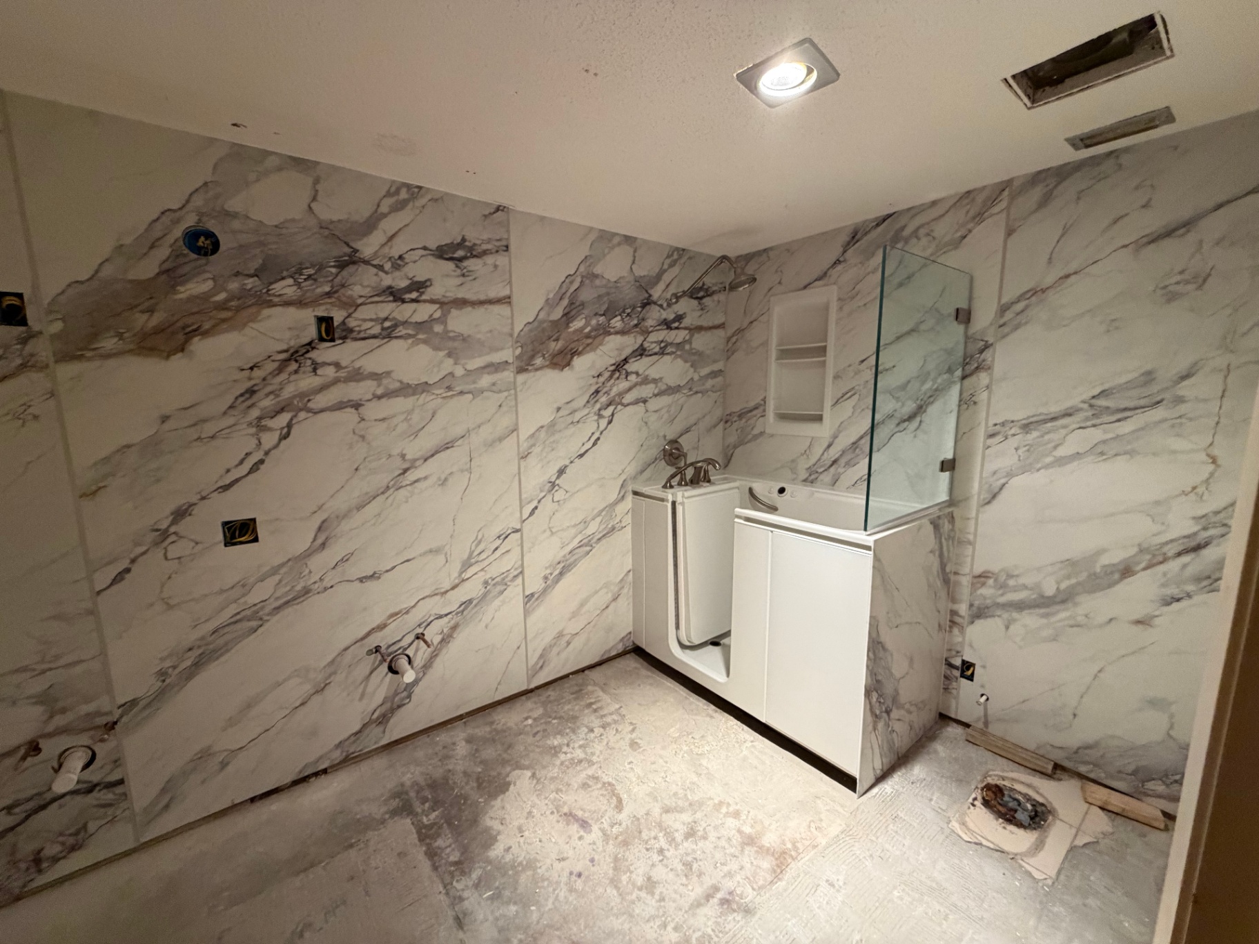 Walk-in tub installation with veined marble-look acrylic wall panels