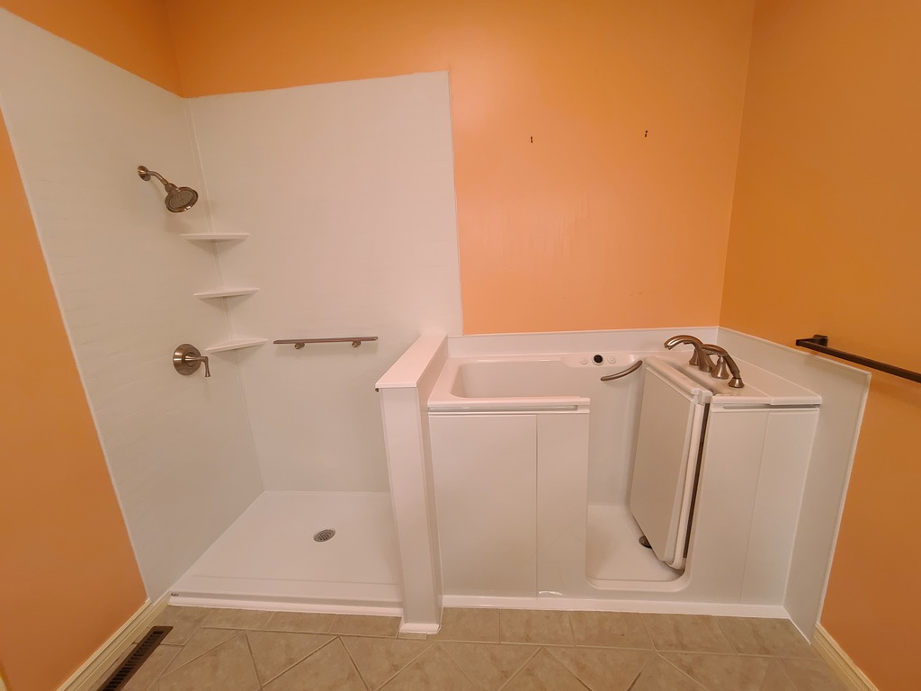 Accessible walk-in tub paired with a low-threshold roll-in shower with grab bar