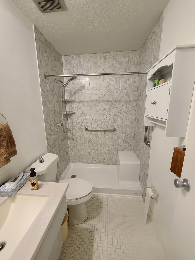 Marble-look acrylic tub-shower combo with safety grab bars and corner caddy